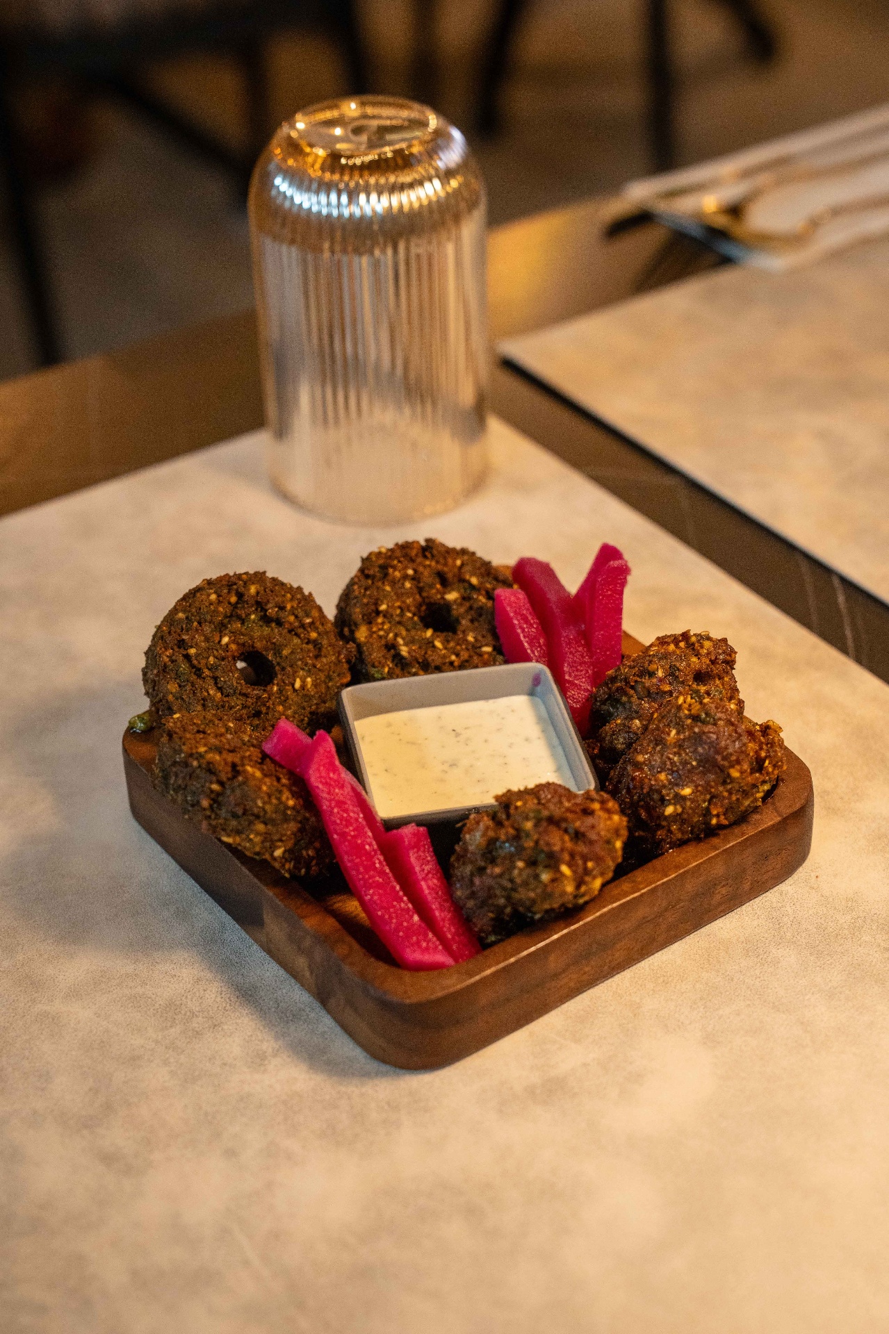 Crispy falafel and pickled turnips with tahini dip on a wooden board