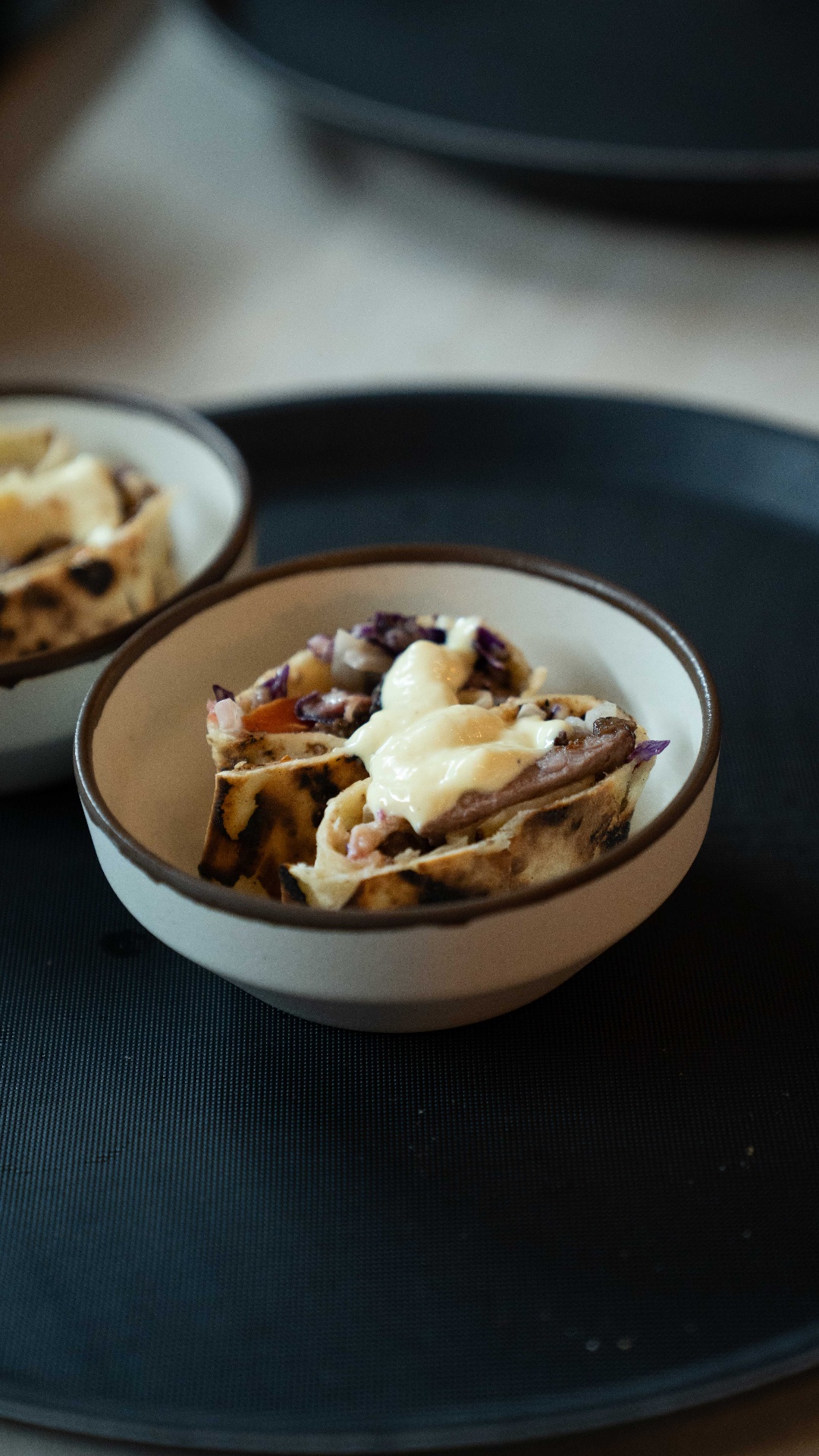 Sliced shawarma served in a ceramic bowl with garlic sauce