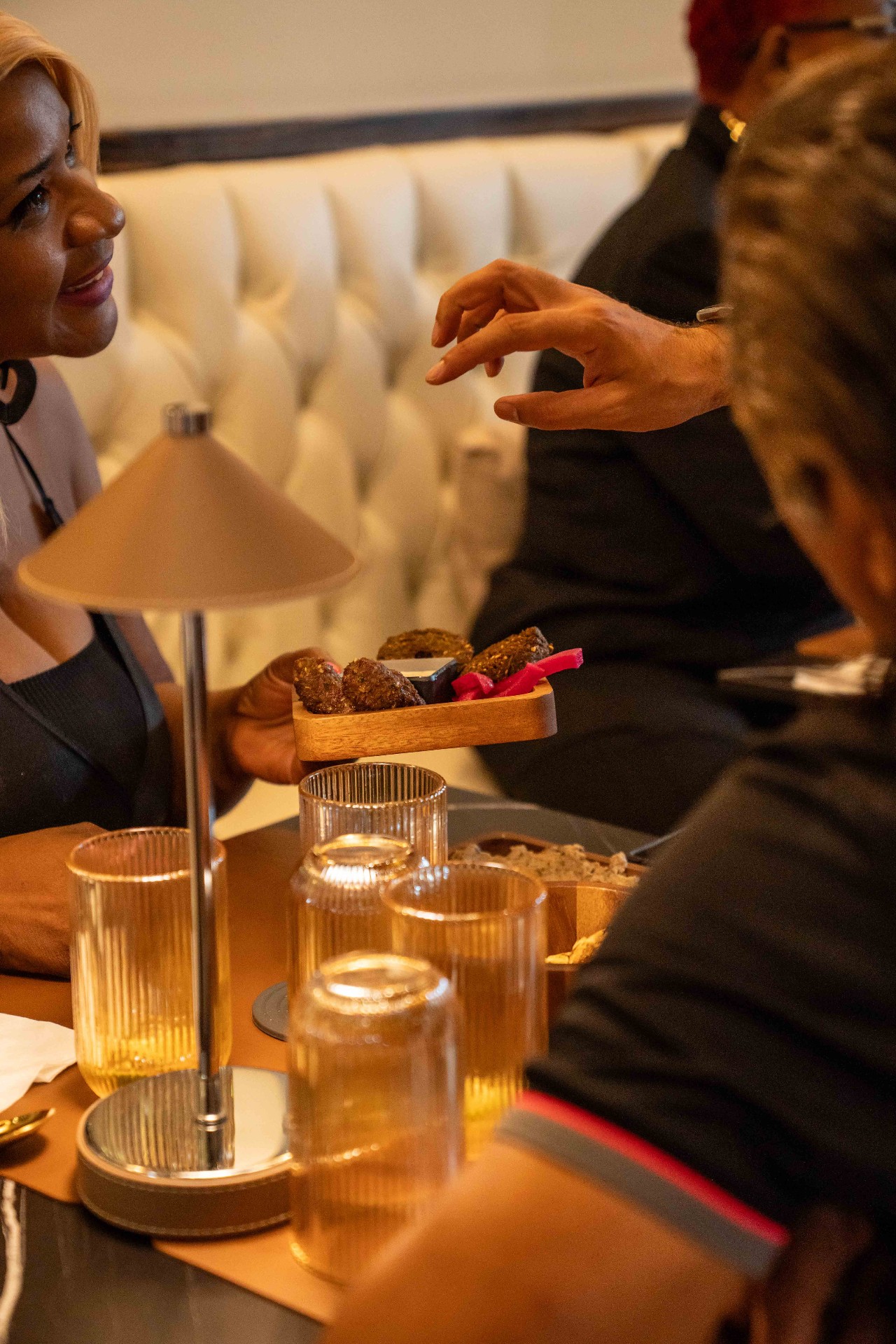 Guests sharing falafel and drinks in the warm dining room