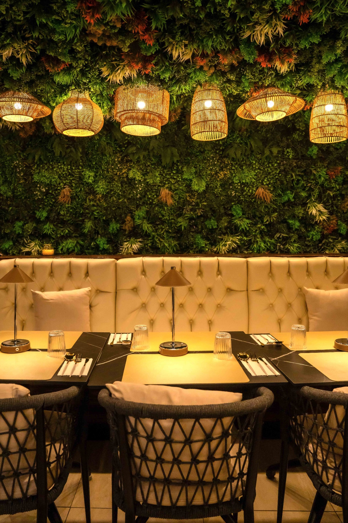 Warm interior of Yallah Shawarma & Hookah with rattan pendant lights and a lush green wall