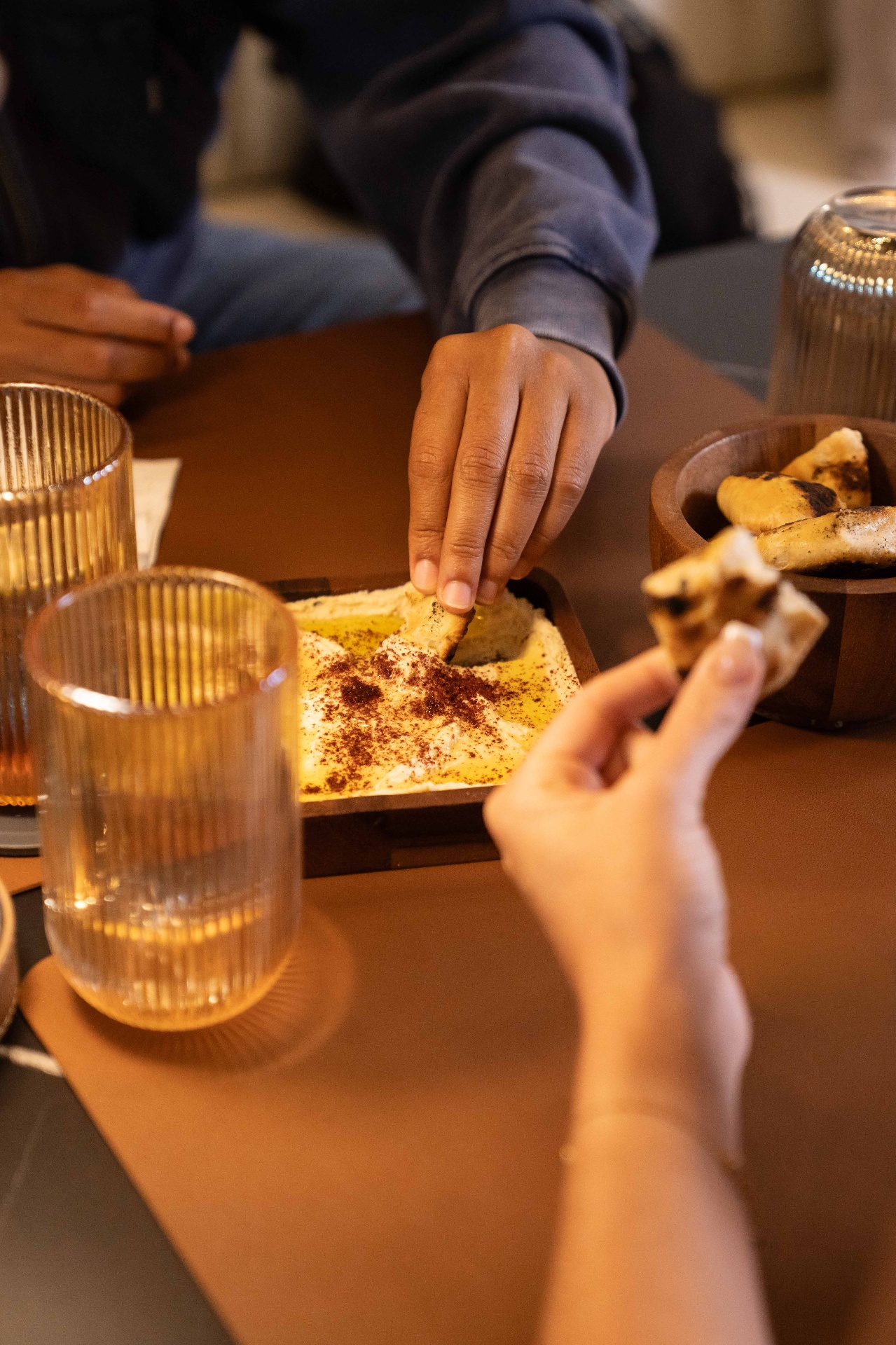 Friends sharing fresh hummus and warm pita at the table
